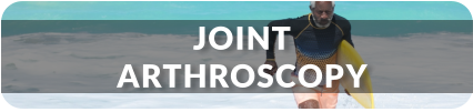 A senior man jogs out of the ocean onto the beach with a surfboard under his arm. Title reads: Joint Arthroscopy